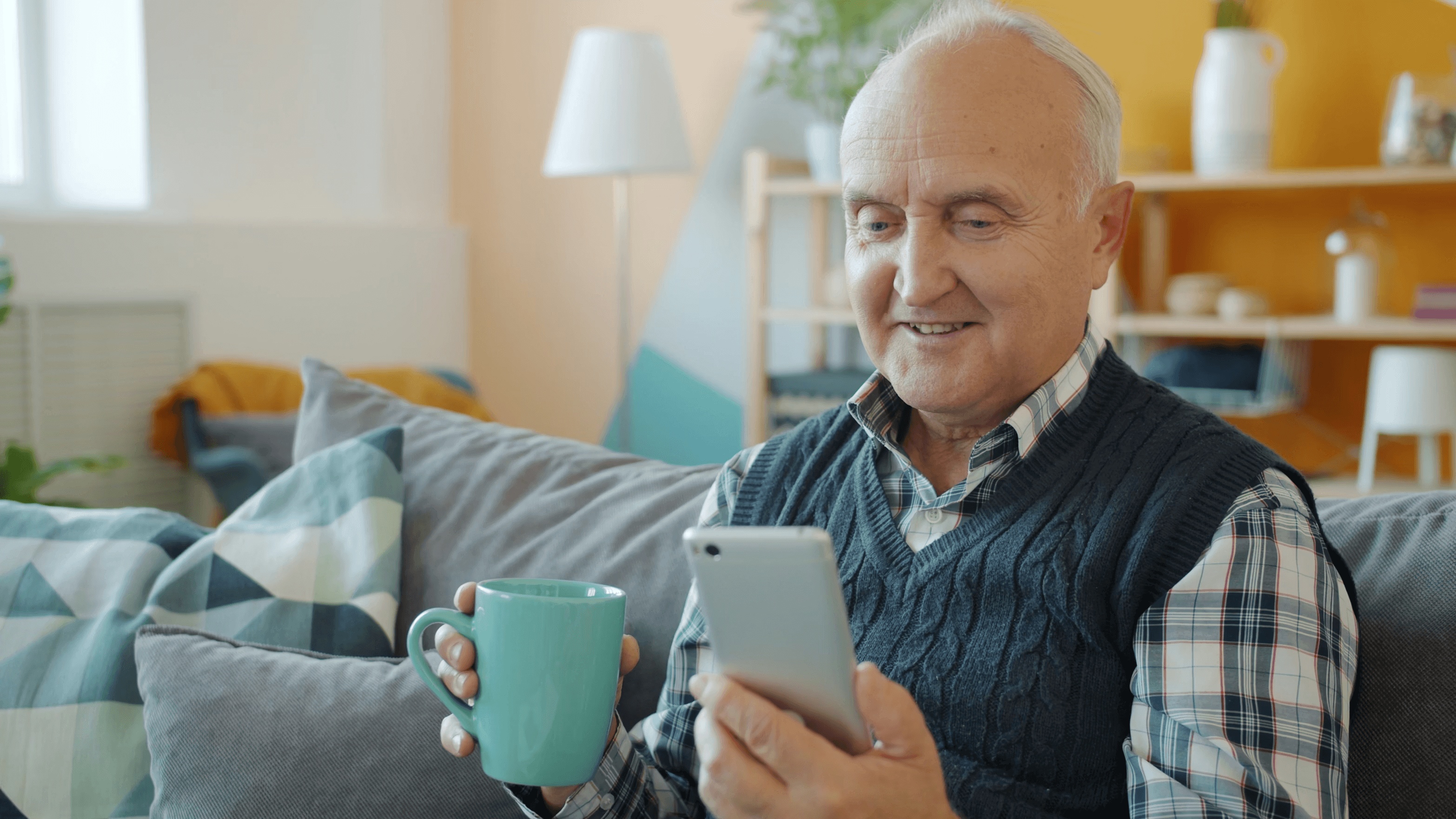 Senior man sitting at home using a phone